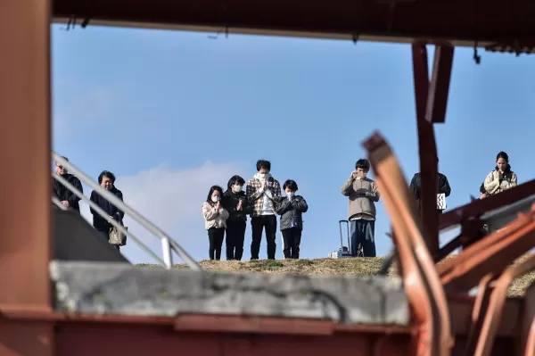Le persone pregano mentre prendono parte al silenzio di un minuto per ricordare le vittime nel 14 ° anniversario del terremoto del 2011, dello tsunami e del disastro nucleare. Foto di STR/Jiji Press/AFP tramite Getty Images.